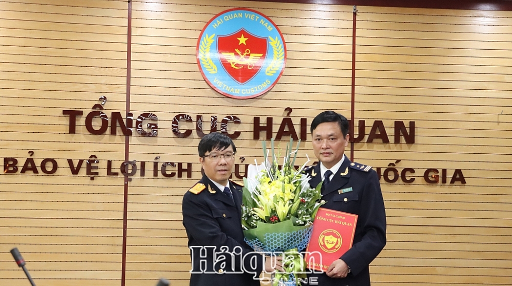 Phó Tổng cục trưởng Lưu Mạnh Tưởng tra quyết định và tặng hoa cho tân Phó Cục trưởng Cục Thuế XNK. Ảnh: H.Nụ
